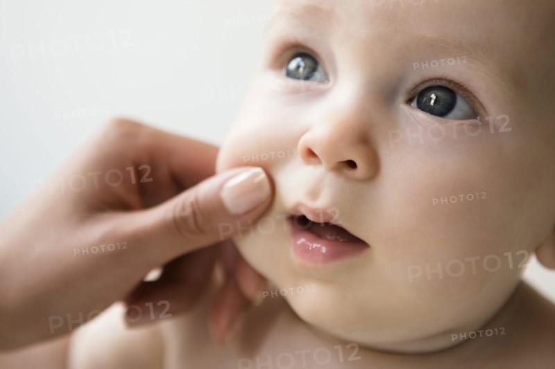 Hand of mother pinching cheek of baby son