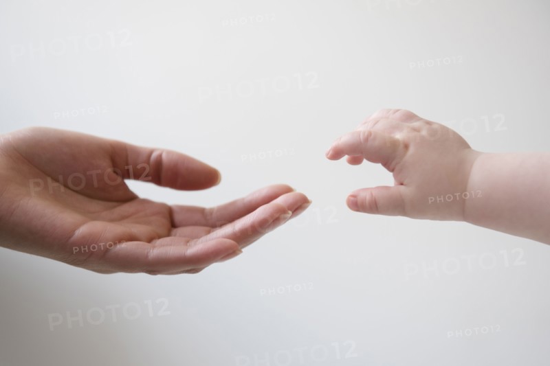 Hand of mother reaching for hand of baby son