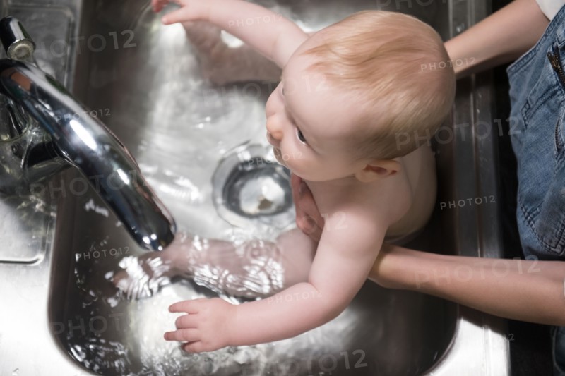 Mother bathing Caucasian baby son in sink
