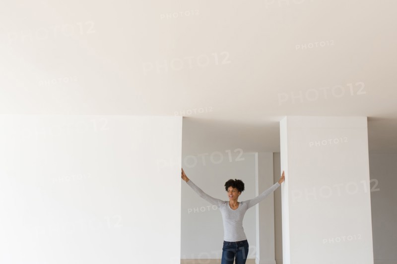 Black woman leaning in doorway in empty apartment