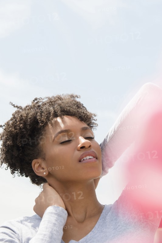 Black woman rubbing neck outdoors
