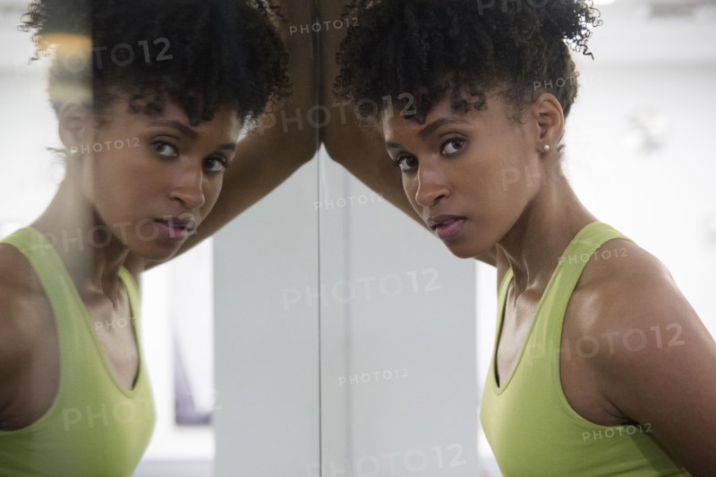 Serious Black woman leaning on mirror wall