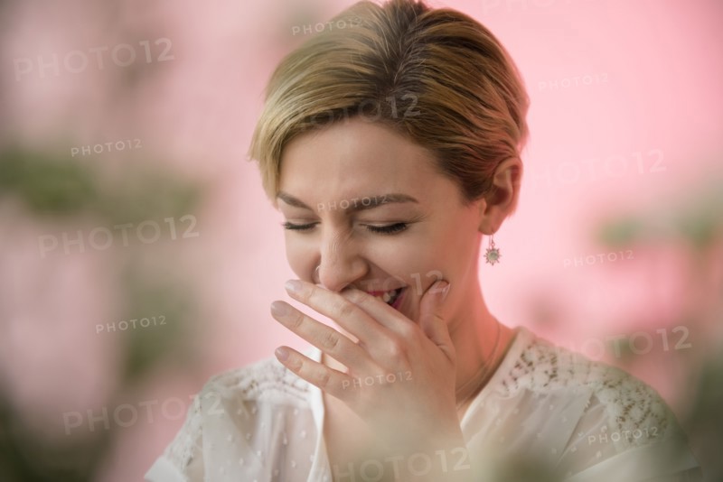 Caucasian woman covering mouth while laughing