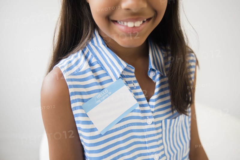 Smiling Mixed Race girl wearing name badge