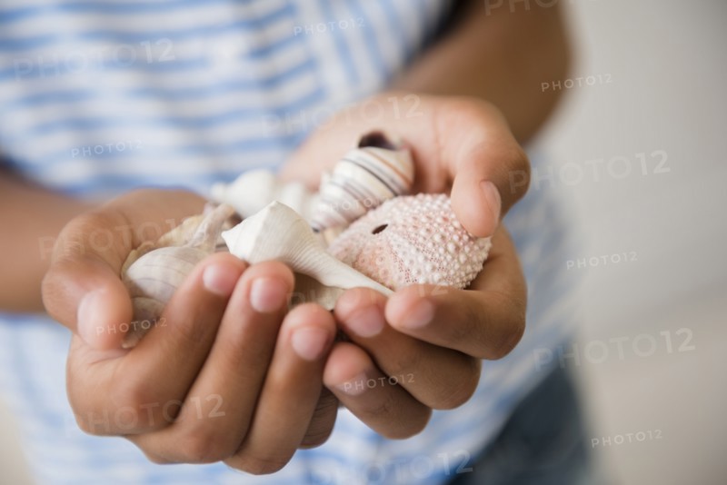 Mixed Race girl holding handful of seashells