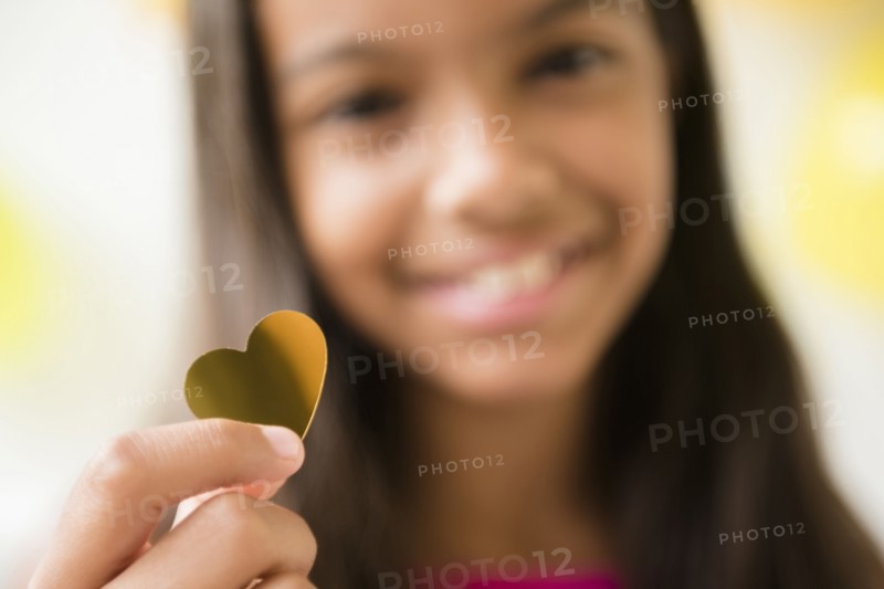 Mixed Race girl holding golden heart-shape confetti