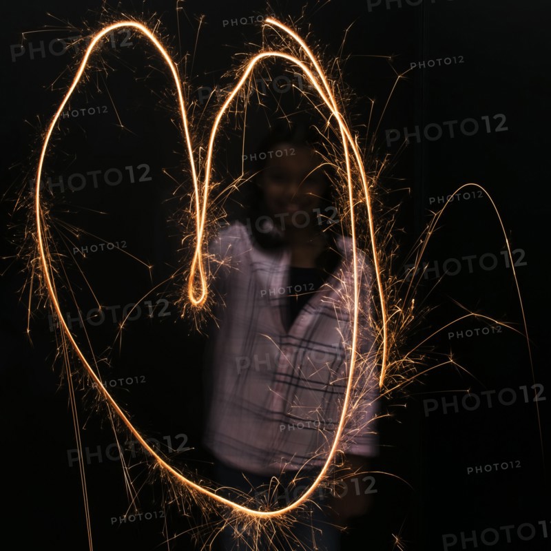 Mixed Race girl making heart-shape with sparkler