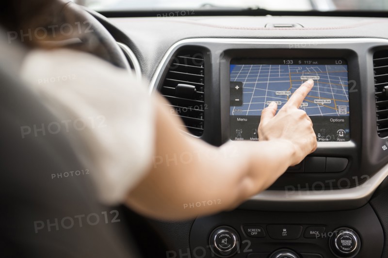 Mixed Race woman using touch screen navigation map in car