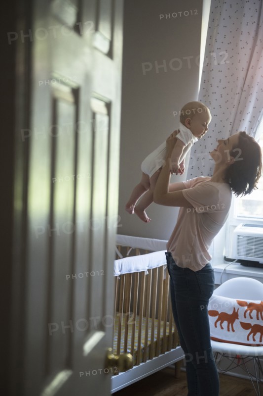 Caucasian mother holding baby son face to face in bedroom