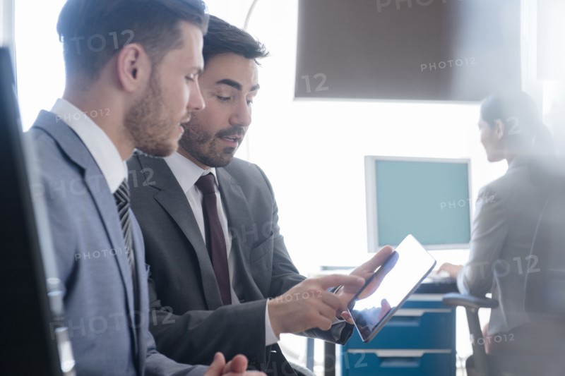 Businessmen using digital tablet in office