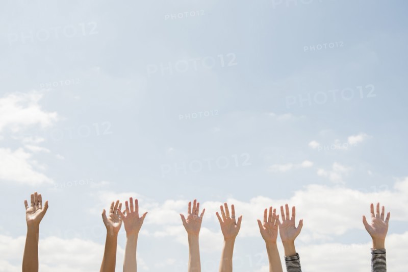 Raised hands of women outdoors