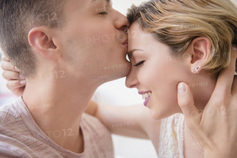 Caucasian man kissing girlfriend on forehead