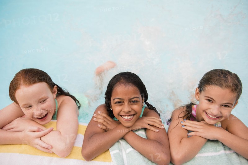 Smiling girls posing at the edge of swimming pool