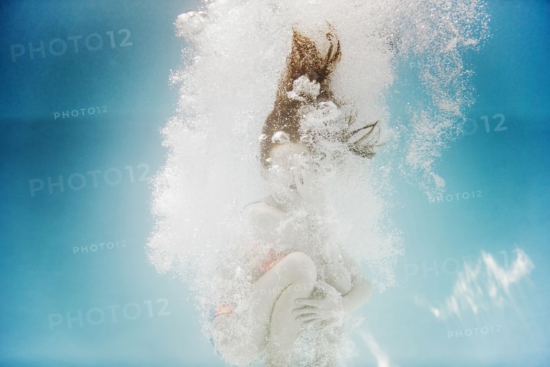 Caucasian girl swimming underwater holding nose
