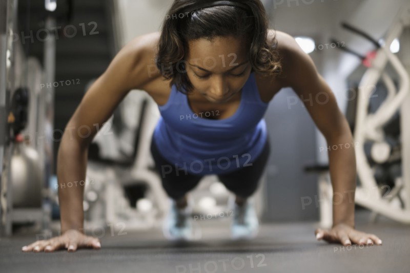 Mixed Race woman doing push-up on floor at gymnasium