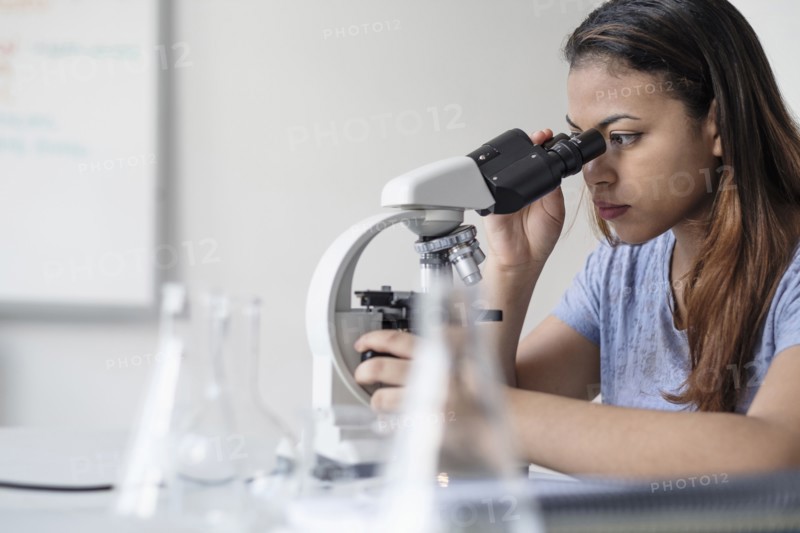 Hispanic woman using microscope