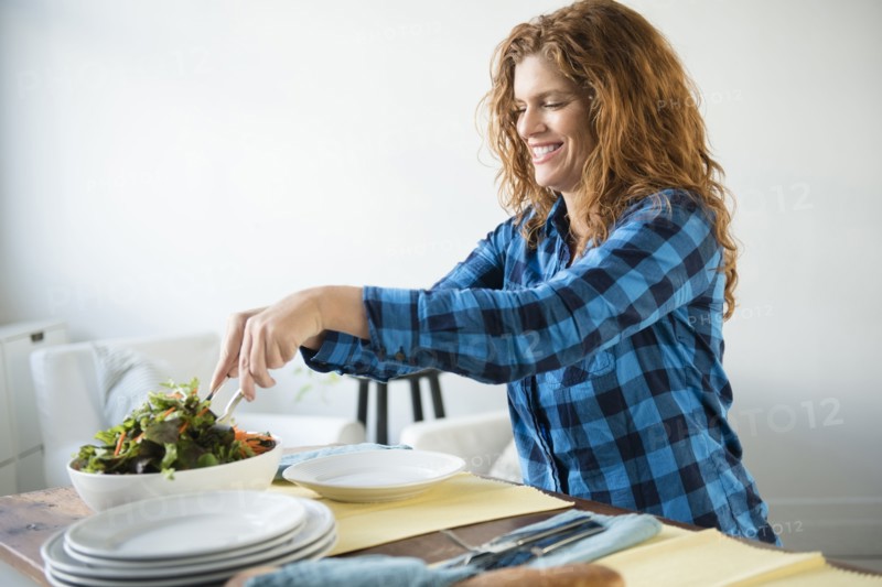 Smiling Caucasian woman tossing salad
