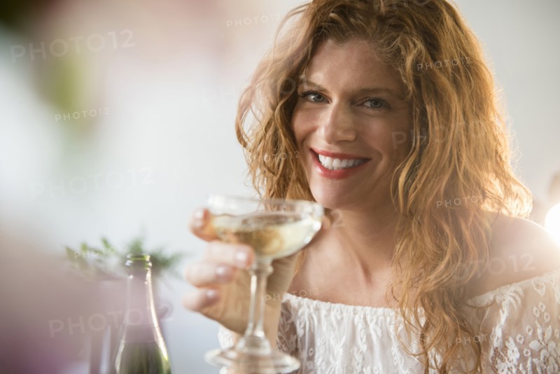 Smiling Caucasian woman drinking champagne in coupe
