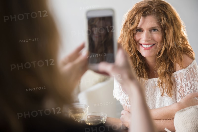 Friend photographing Caucasian woman with cell phone
