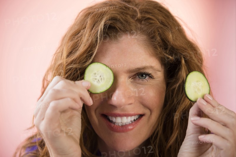 Smiling Caucasian woman covering eye with cucumber slice
