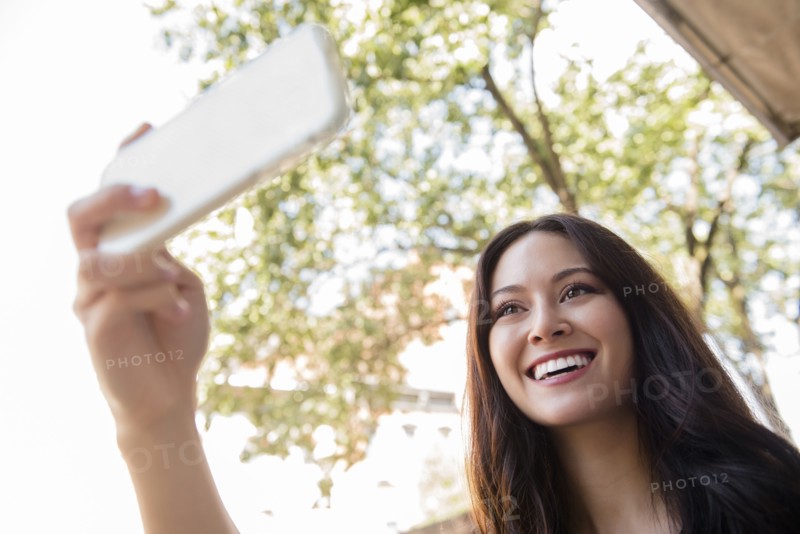 Smiling Thai woman posing for cell phone selfie