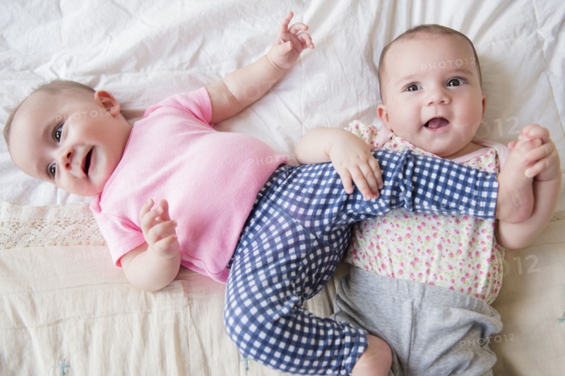 Caucasian twin baby girls playing on bed