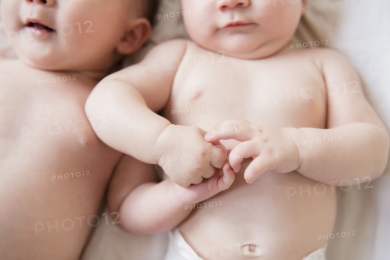 Caucasian twin baby girls holding hands