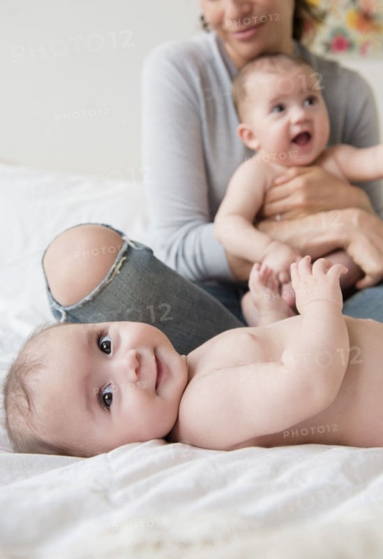 Caucasian mother with twin baby daughters on bed