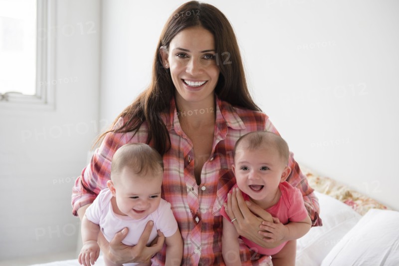 Caucasian mother holding twin baby daughters