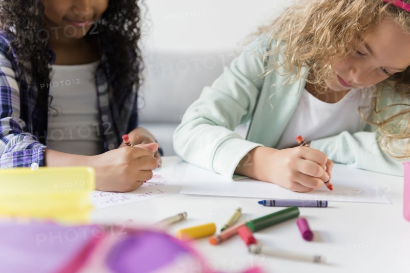 Girls drawing with multicolor crayons