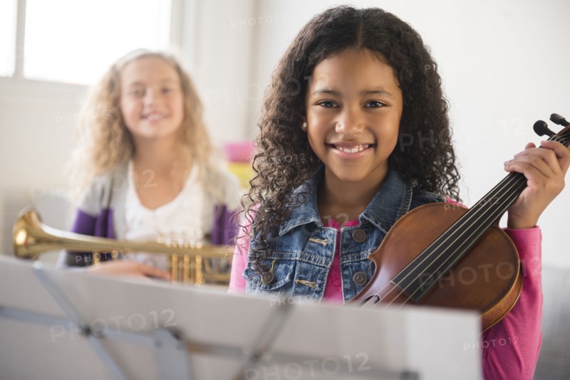Smiling girls posing with violin and trumpet