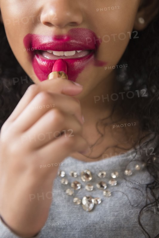 Mixed Race girl applying messy lipstick