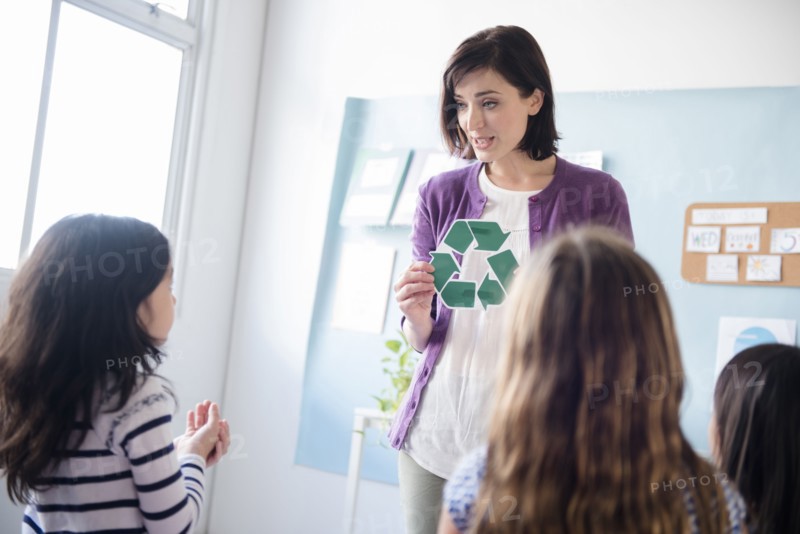 Teacher showing recycling symbol to girls in classroom
