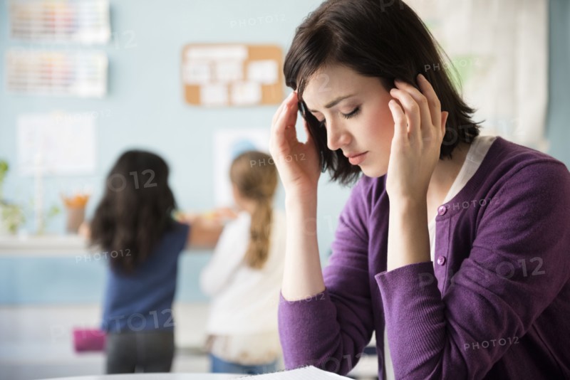 Caucasian teacher with headache in classroom