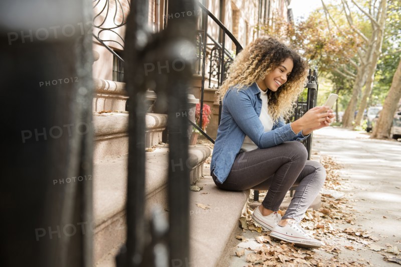 Mixed Race woman in city texting on cell phone