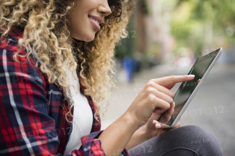Mixed Race woman using digital tablet in city