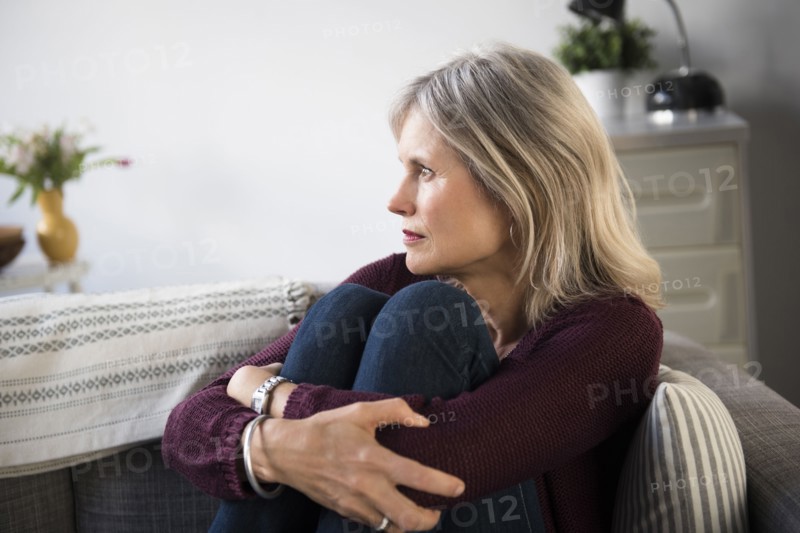 Worrying Caucasian woman hugging legs