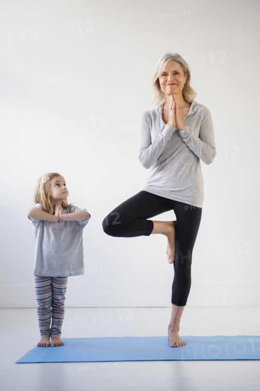 Caucasian granddaughter watching grandmother practicing yoga