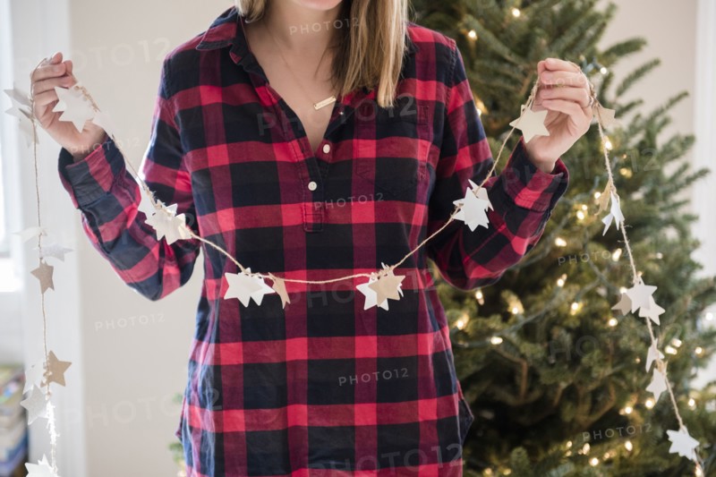 Caucasian woman holding Christmas ornaments on string