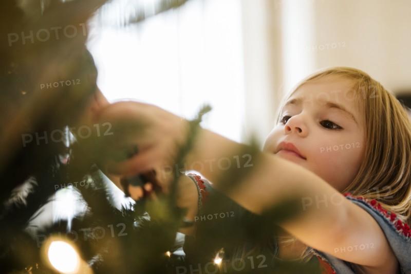 Caucasian girl hanging lights on Christmas tree