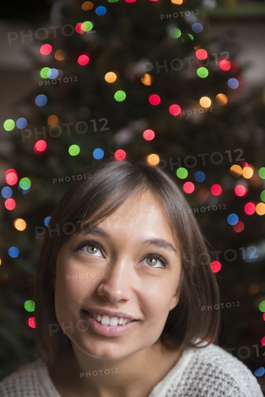 Pensive Mixed Race woman near Christmas tree