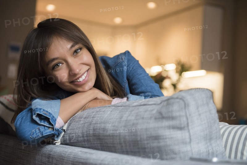 Smiling Mixed Race woman leaning on sofa