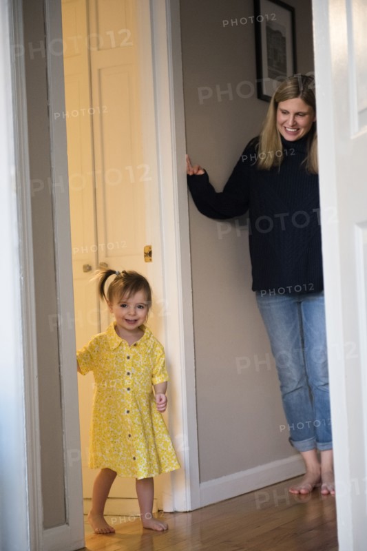 Mother watching Caucasian baby daughter standing in doorway