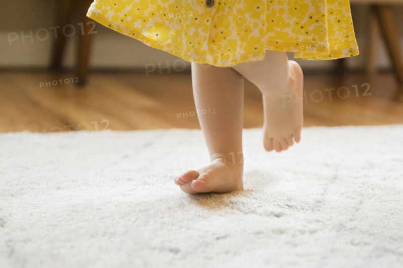 Barefoot Caucasian baby girl walking on rug