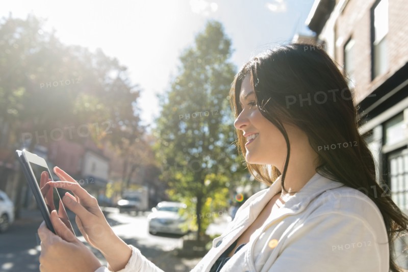 Caucasian woman using digital tablet in city