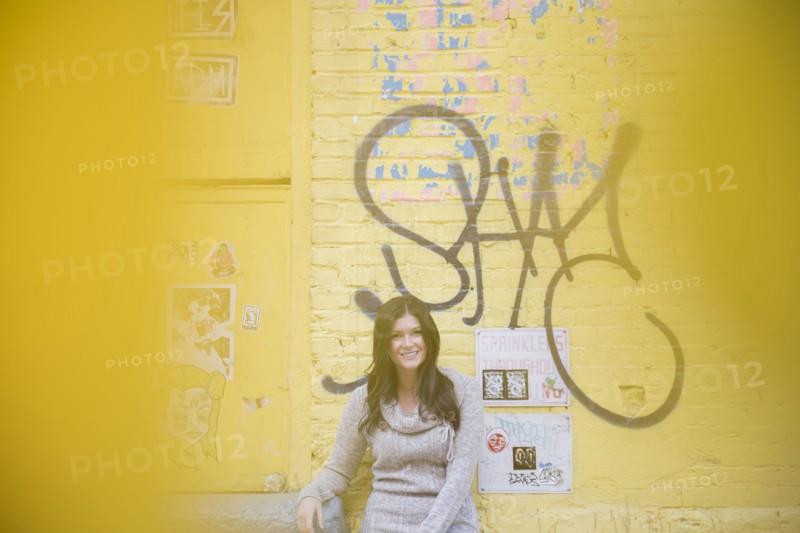 Caucasian woman leaning on yellow graffiti wall