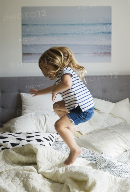 Caucasian girl jumping on bed