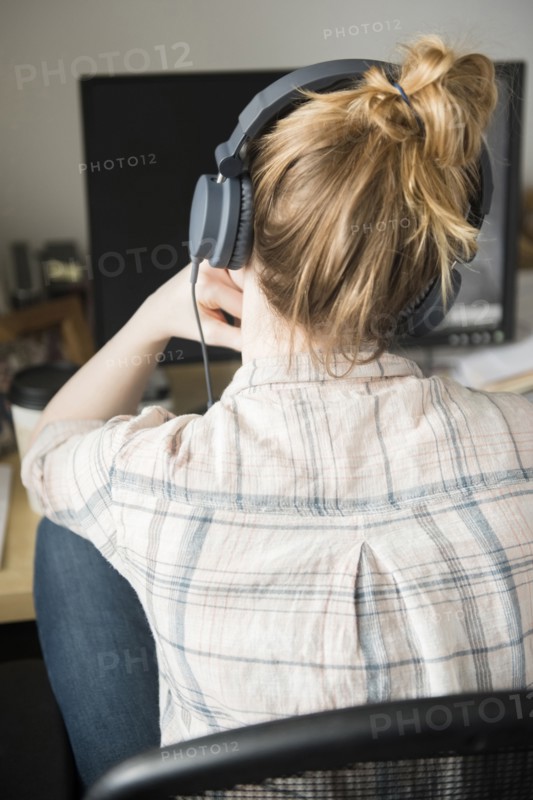 Woman using computer and listening to headphones