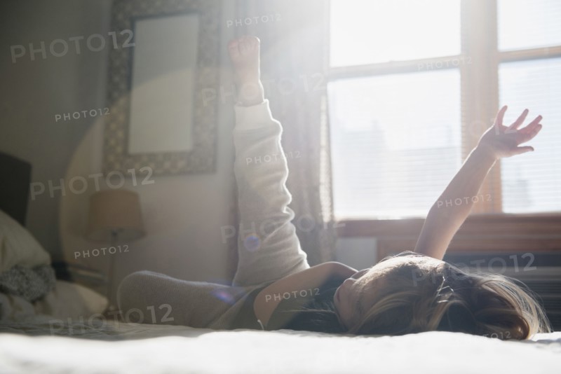 Caucasian girl playing on bed
