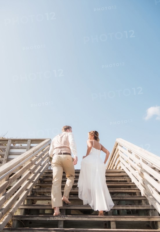 Caucasian bride and groom climbing wooden staircase